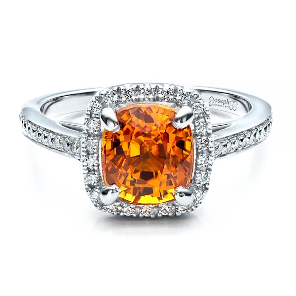 Fire-looking orange sapphire stone with diamonds in a silver frame isolated in a white background