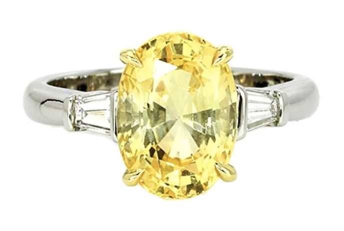 Shiny yellow sapphire stone with a thick silver body isolated on a white background