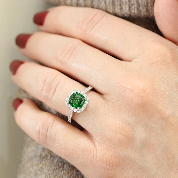 A girl with a proposal green garnet ring which surrounded with mini diamonds