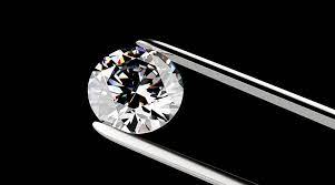 The most expensive round diamond cut holding using a metal holder against a black background