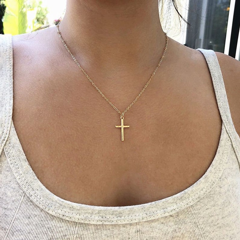 The girl in the gray sleeveless undershirt wearing a gold cross necklace