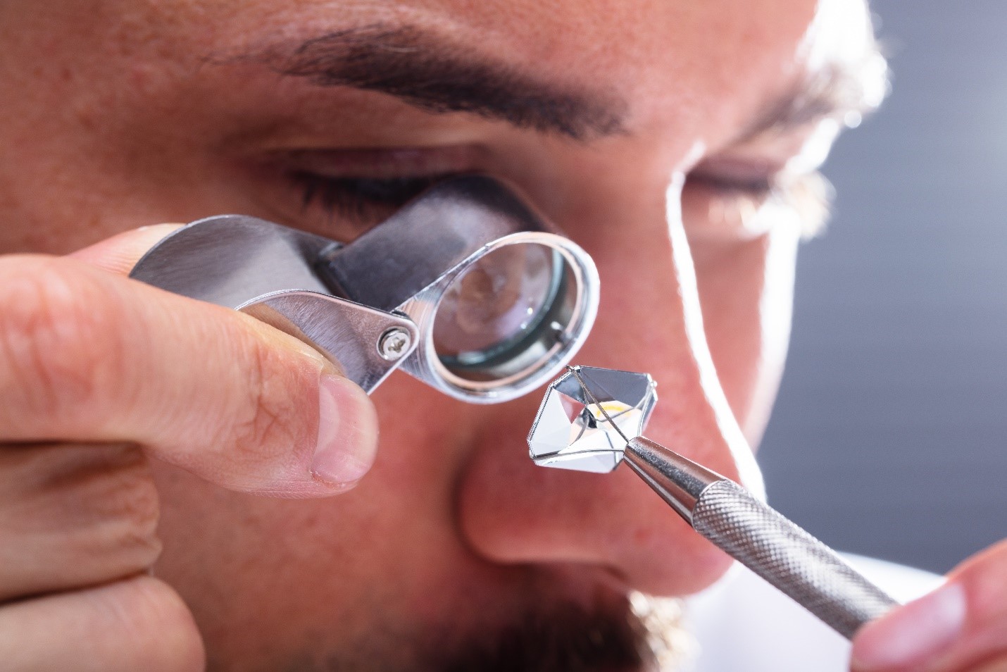 A gemologist examines the clarity of a diamond using a loupe