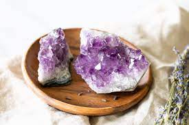 An Amethyst Stone Cracked In Two On A Wooden Plate