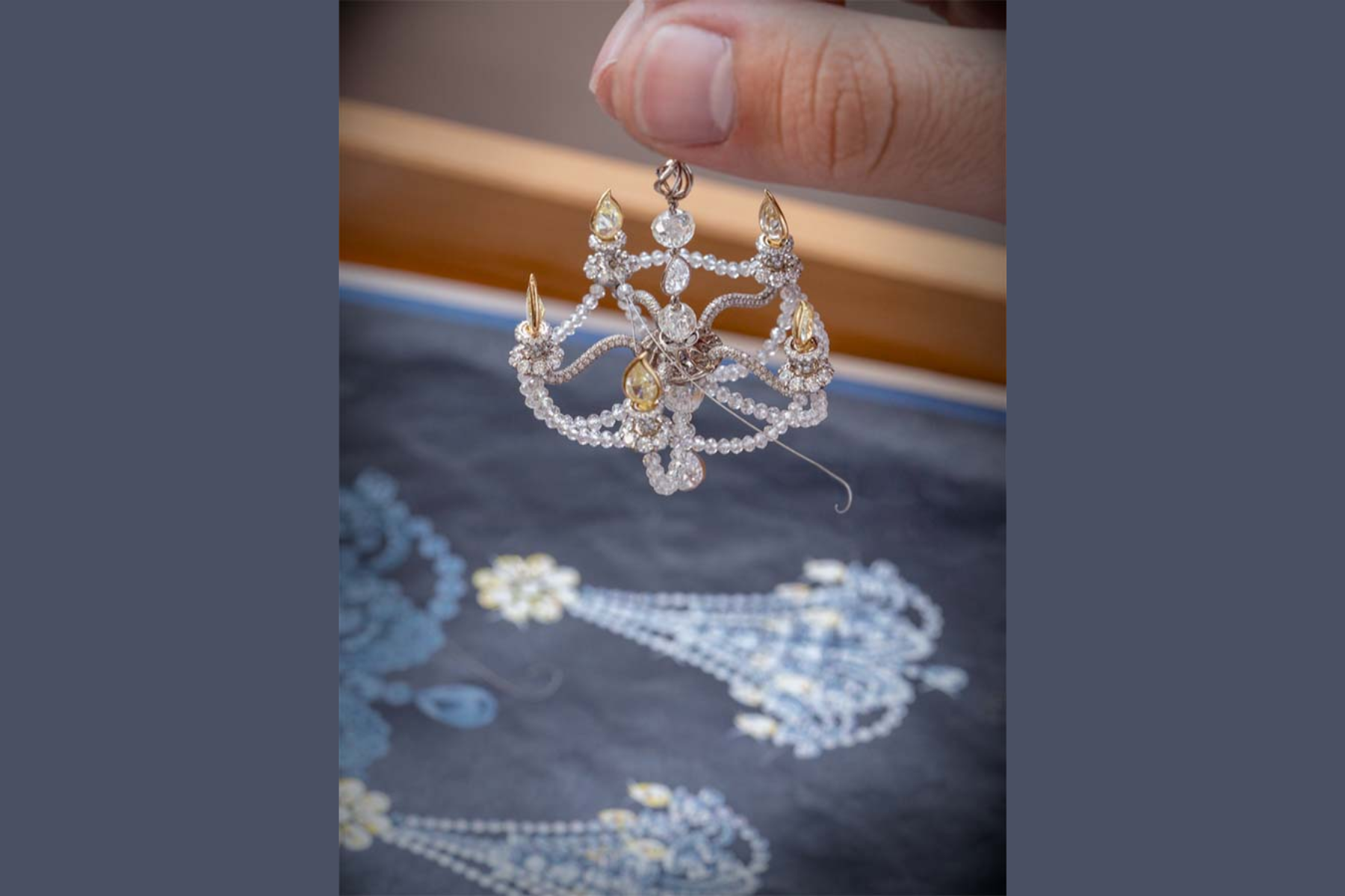 A white hand is holding a Chopard's diamond chandelier earring