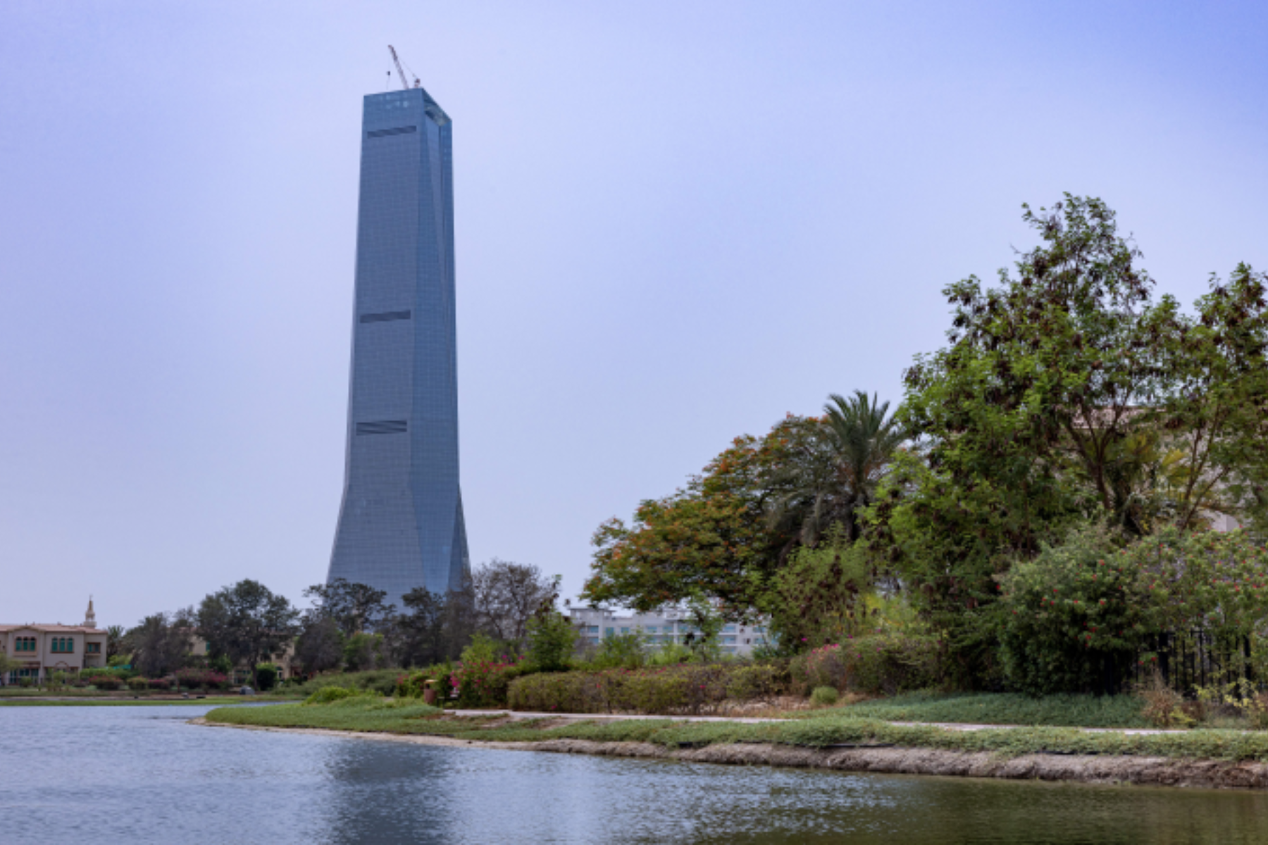 Dubai's DMCC Uptown Tower with trees and a river