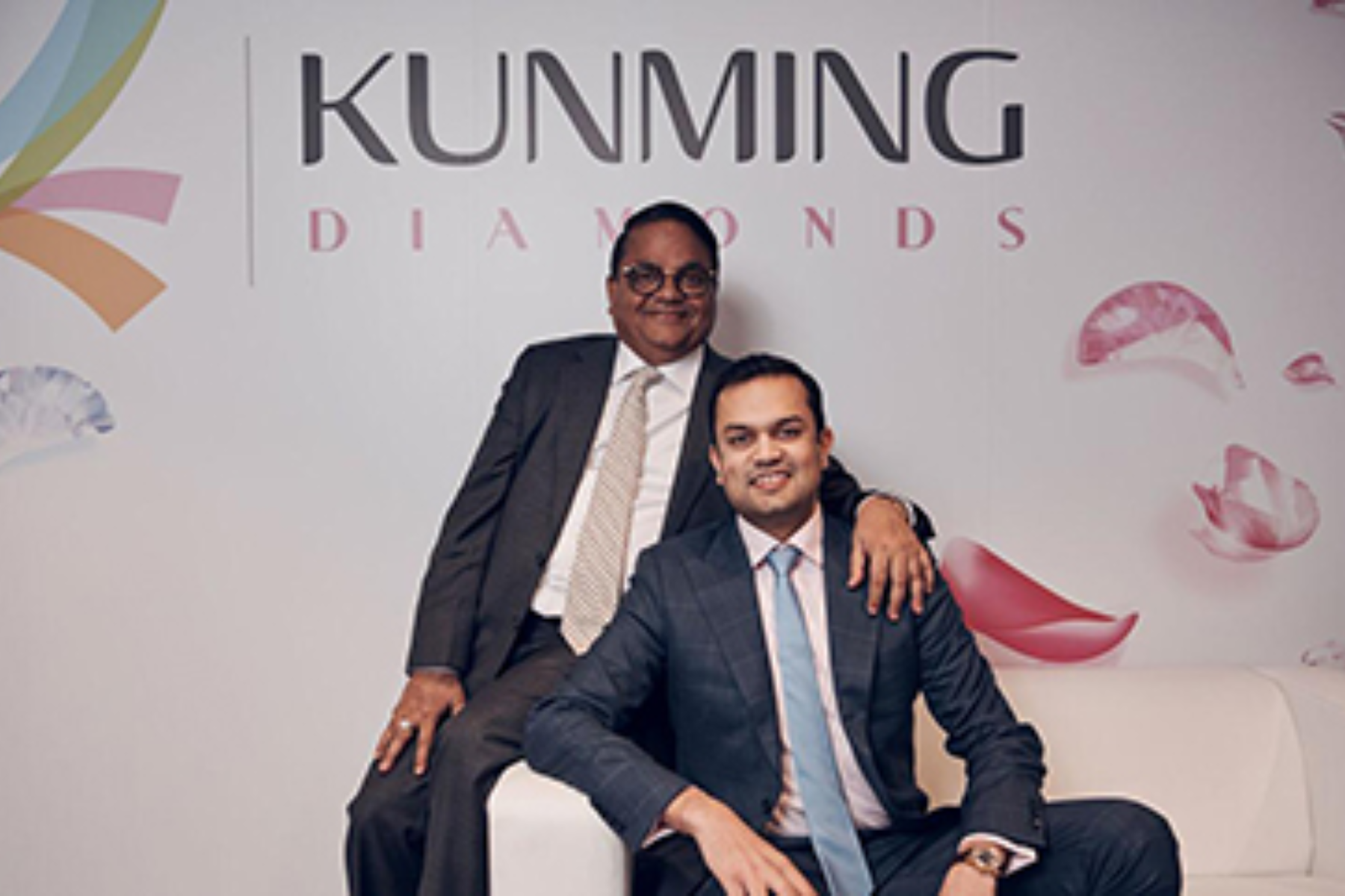 Ajay Maheshwari, the founder of Kunming Diamond, sits on the edge of a sofa, holding his partner's shoulder