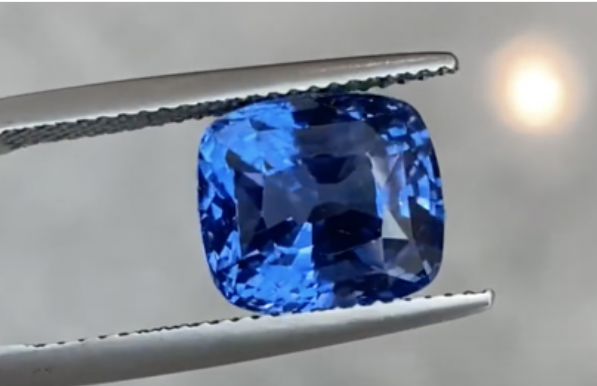A blue rectangularp-shaped sapphire held by a prong