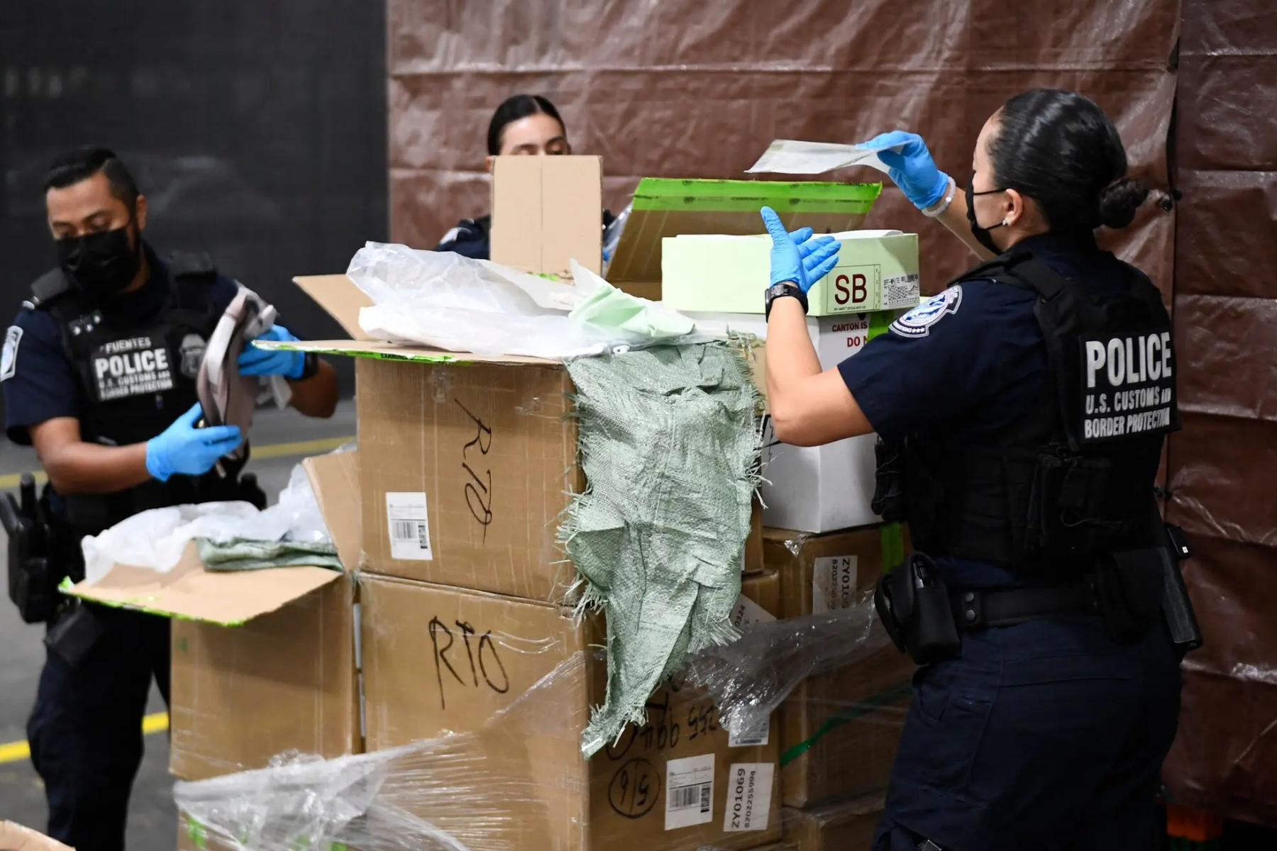Officers from the United States Customs and Border Protection demonstrate a physical inspection of confiscated goods in Los Angeles