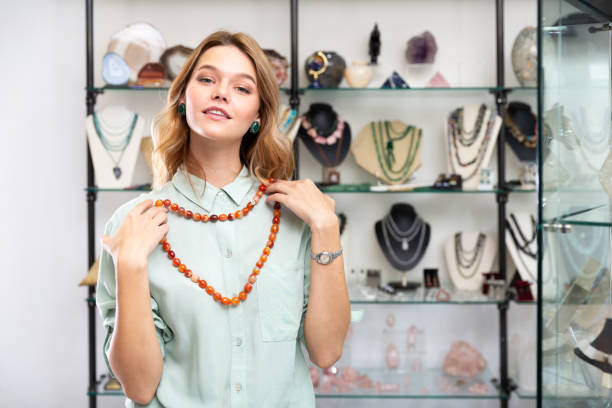 A woman holds a sardonyx necklace in both hands on a jewelry shop