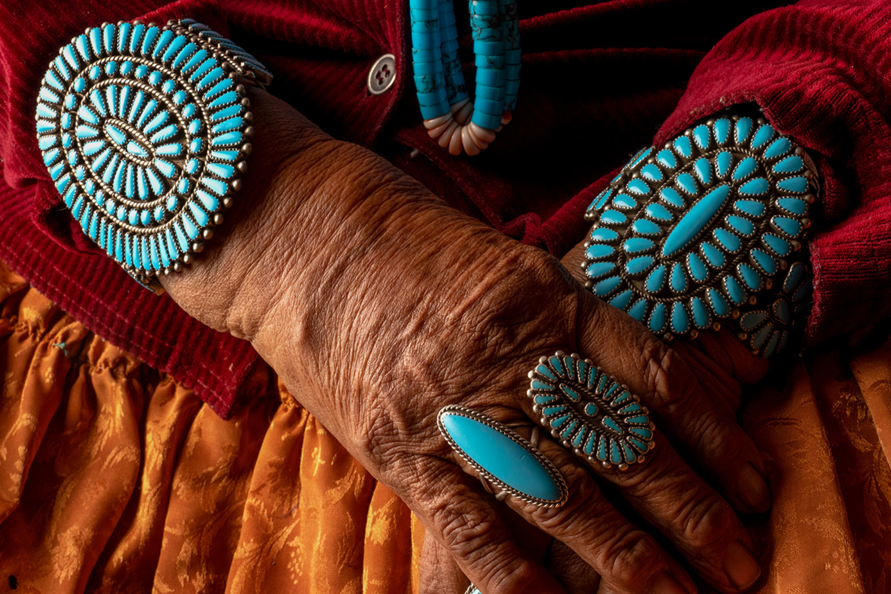 An elderly woman's hand, adorned with turquoise jewelry