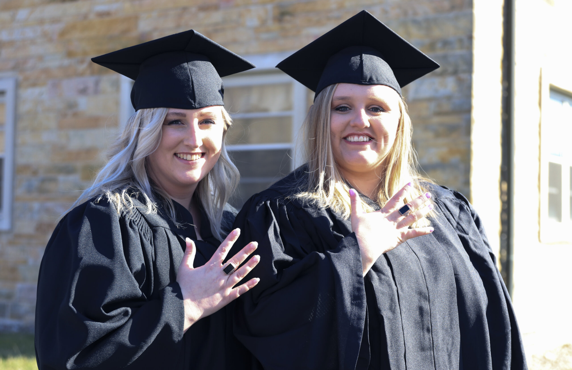 Two female graduates wearing a college ring on their graduation day