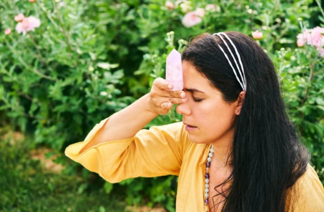 A woman places a Kunzite stone on her forehead to calm herself down