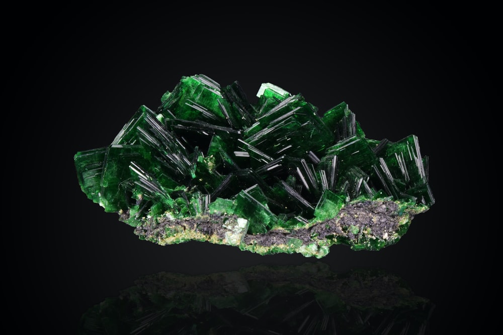 A Piece Of Green Quartz With Its Reflection On The Black Tinted Floor
