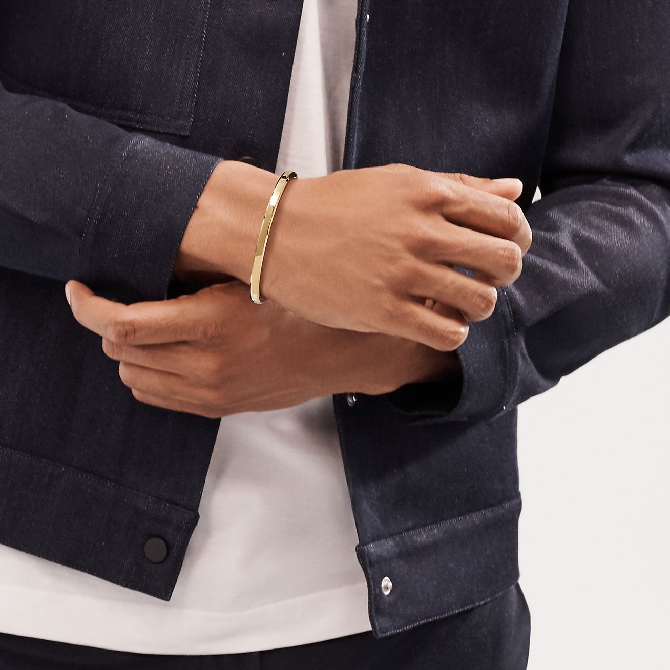 A model wearing a denim jacket and on his wrist is Makers Narrow Cuff in 18k Gold