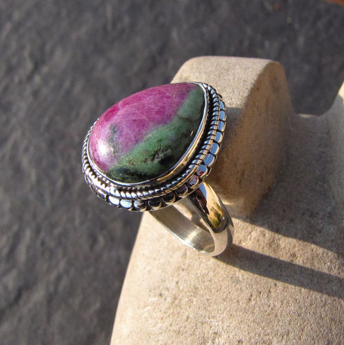 A ring made out of zoisite stone leaning on a stone