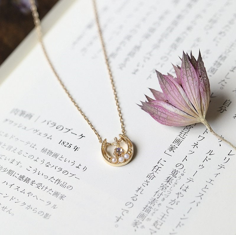 The Lucky Horseshoe Moonstone Necklace and a flower is on the top page of a Chinese notebook