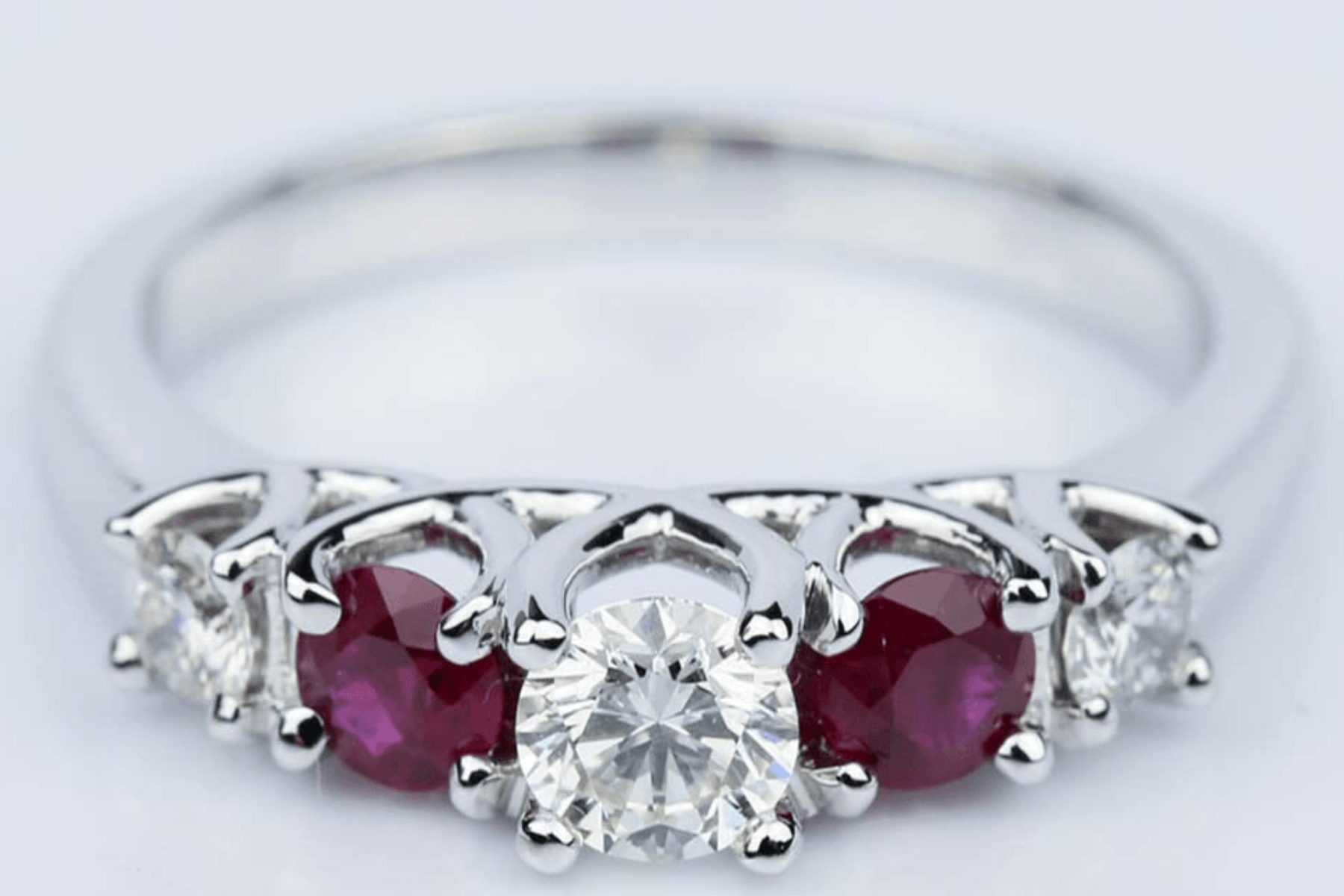 A ring with two red birthstones with diamonds