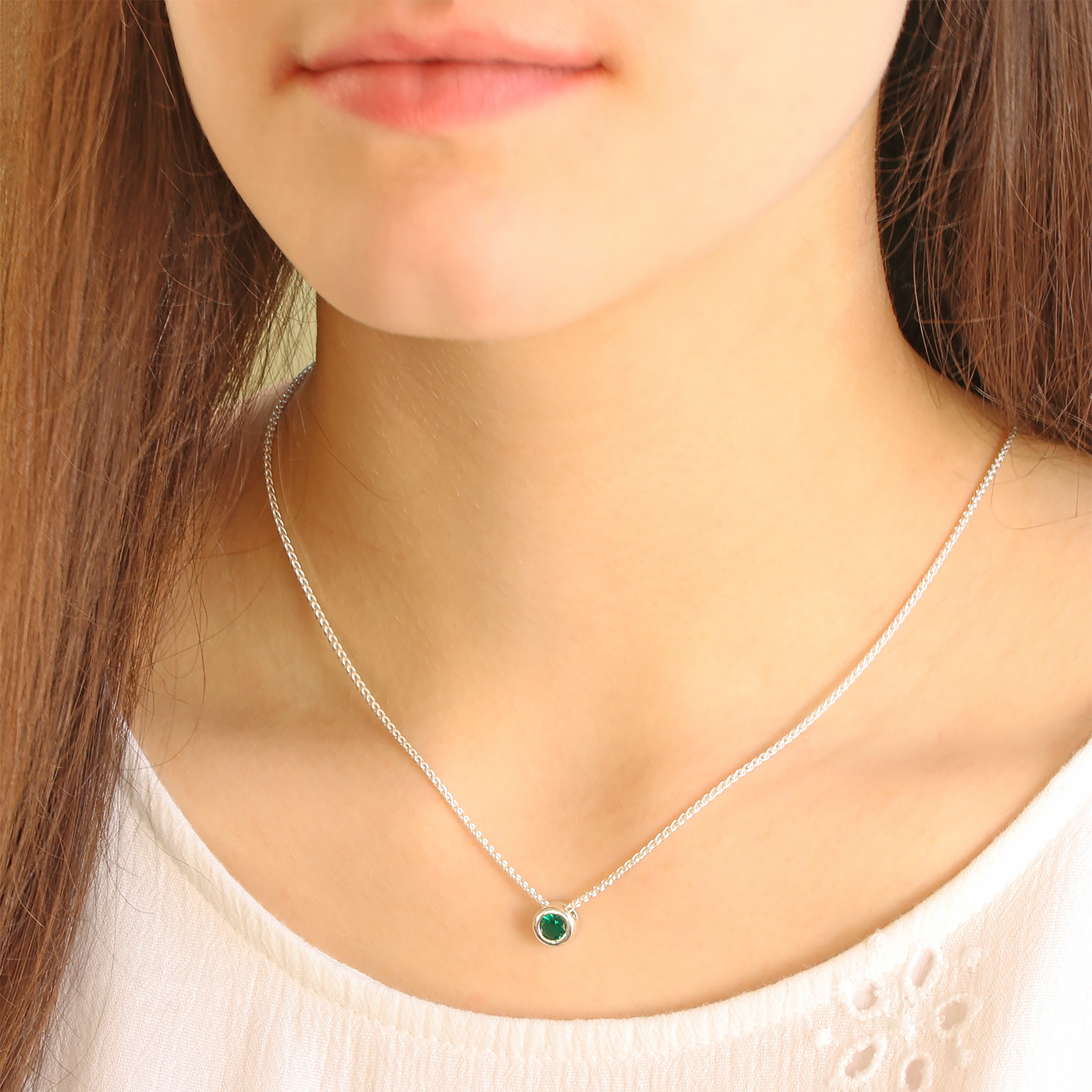 A woman wearing a silver emerald birthstone necklace