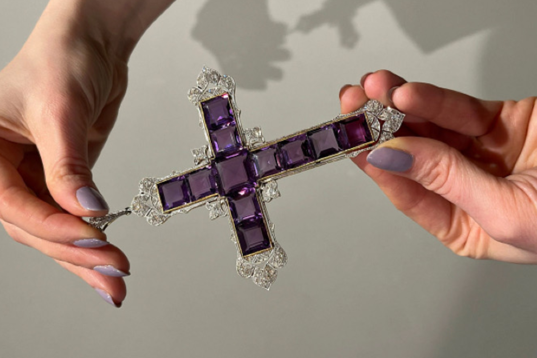 A woman's hand holds the Amethyst Cross pendant that Princess Diana wore