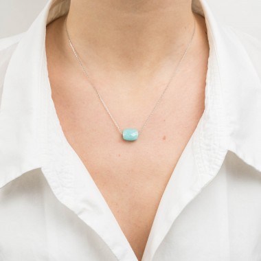 A cushion cut amazonite necklace hangs around the neck of a woman wearing a V-necked shirt