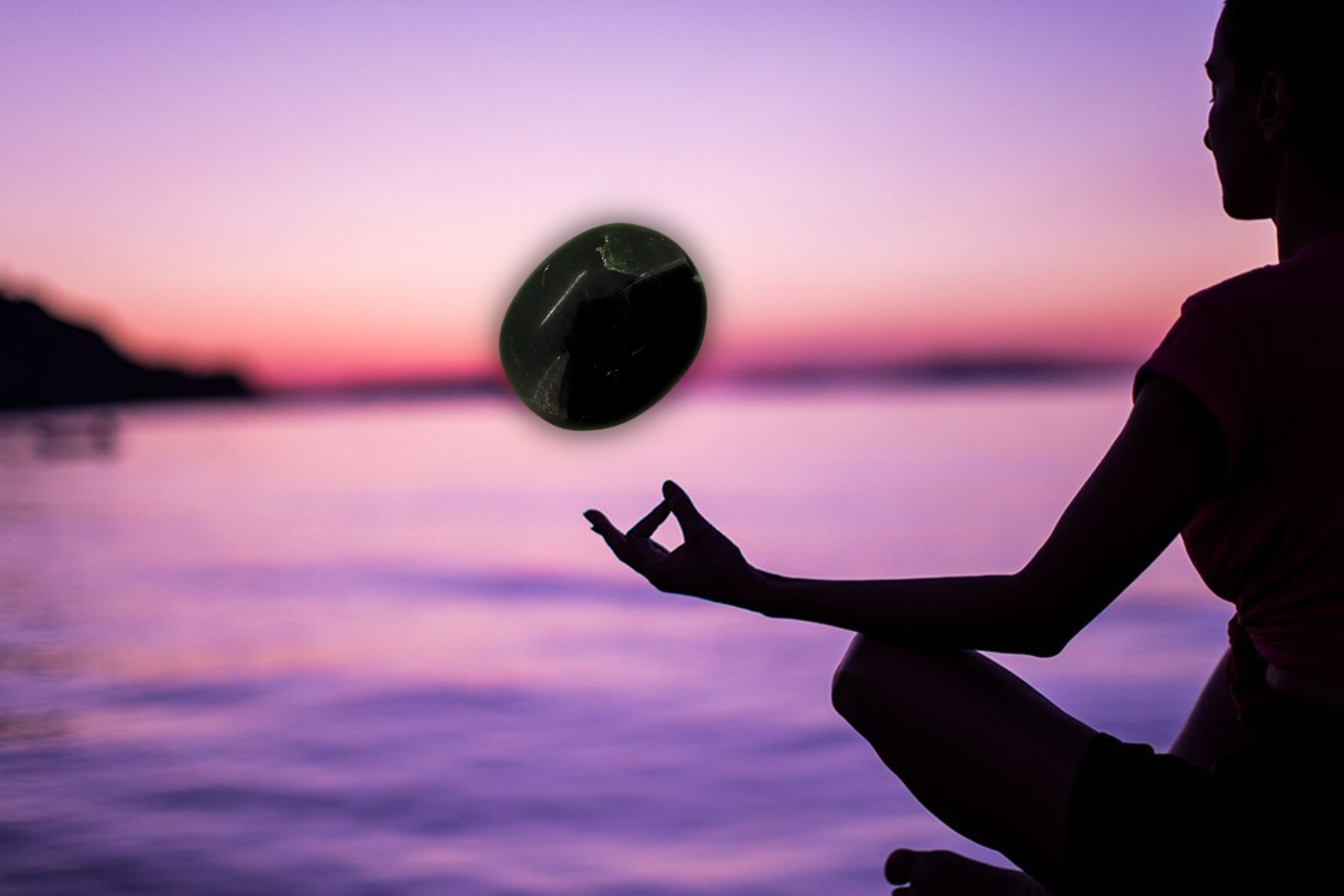 A silhouette of a woman meditating with a floating black agate