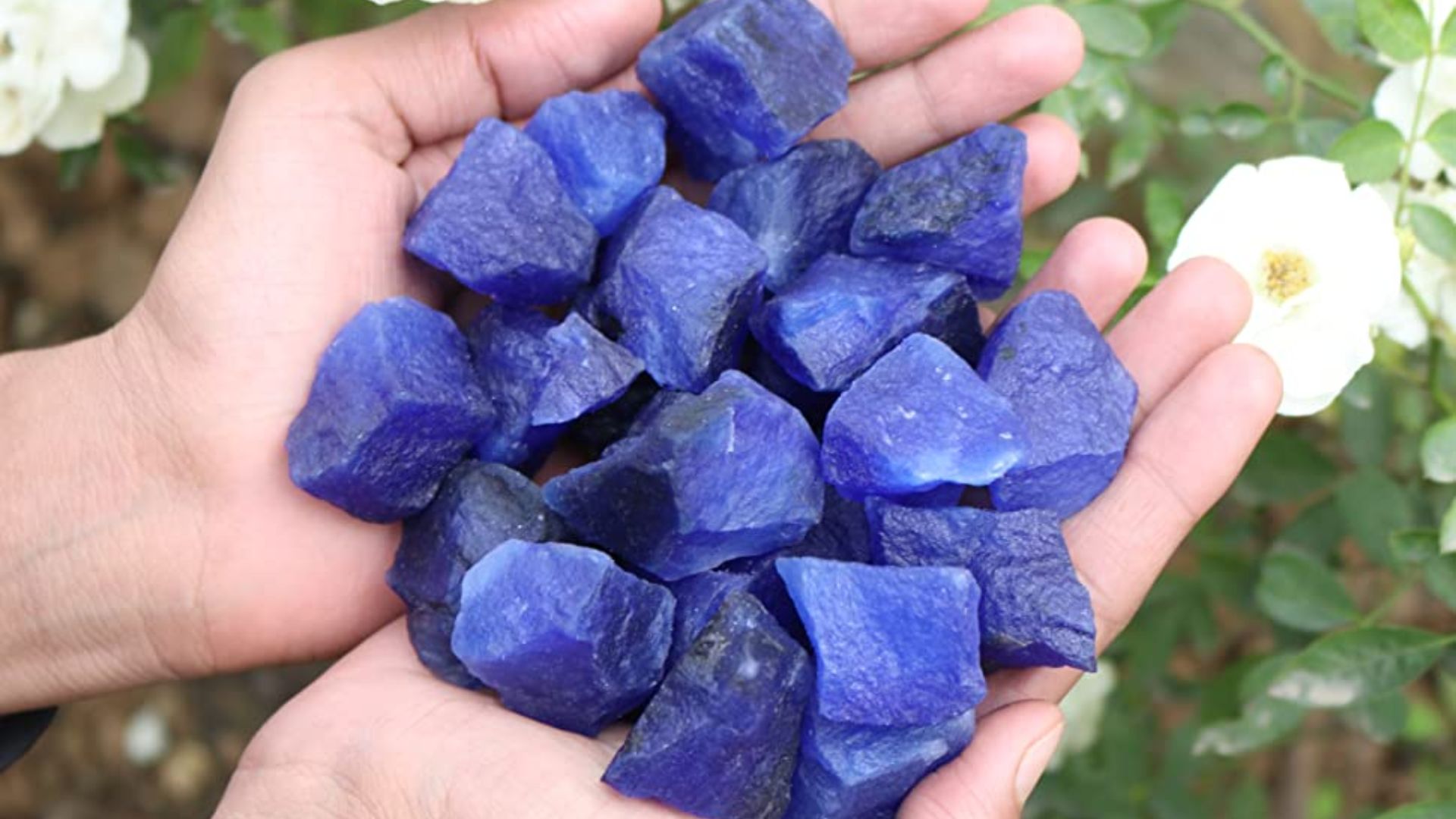Person Holding Blue Gemstones In Hand