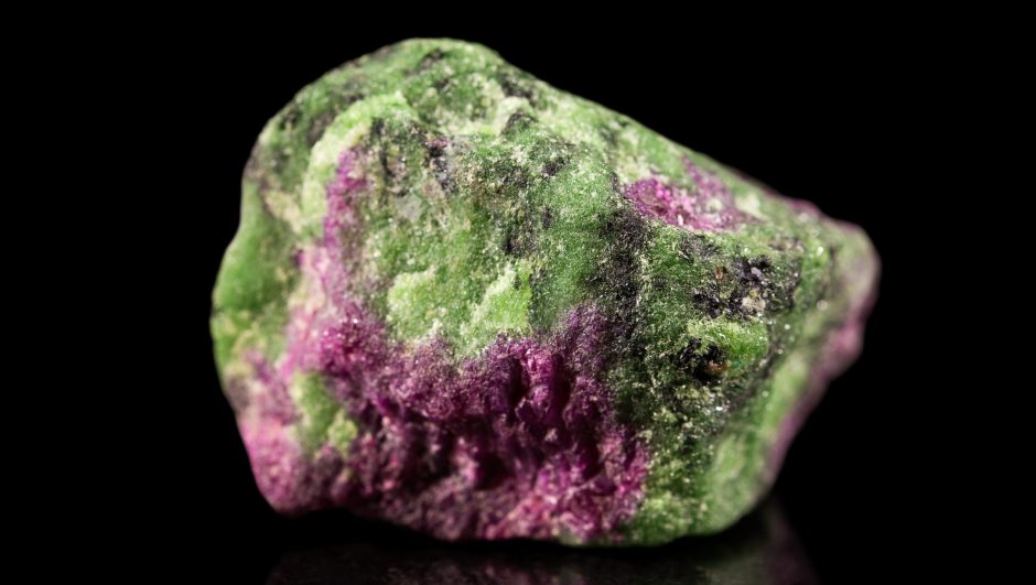 A violet-green zoisite stone on a dark background