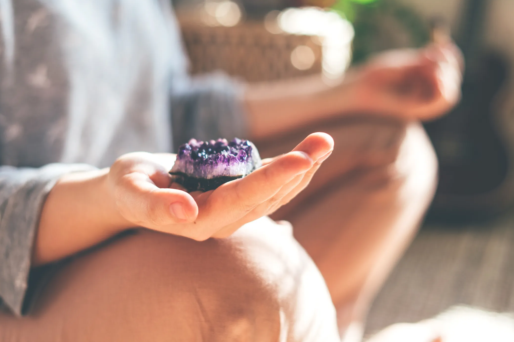 A woman meditates while holding a crystal in her right hand