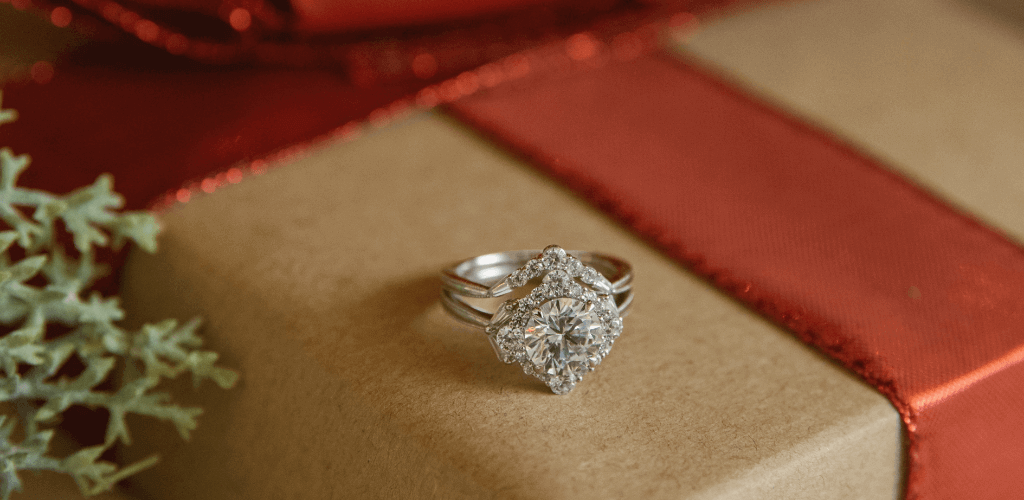 A platinum ring sitting atop a Christmas box