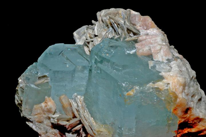 A raw aquamarine that is still attached to its host rock