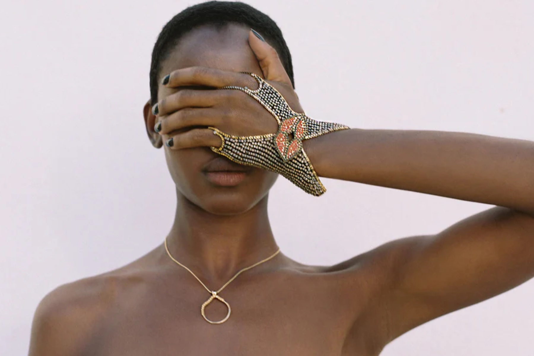 A woman covering her eyes while wearing a customized and unique bracelet and necklace