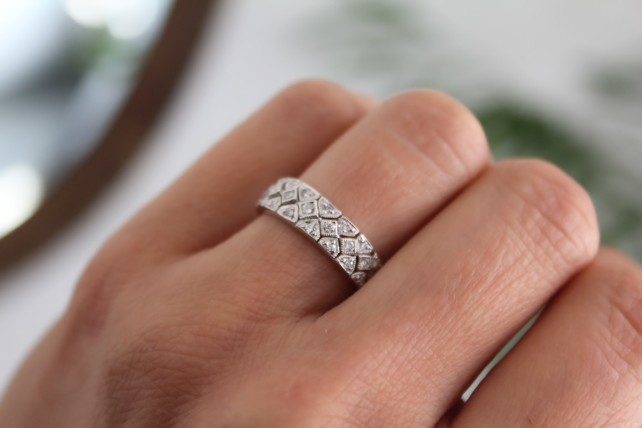 A woman's ring finger is adorned with a platinum ring set with diamond stones