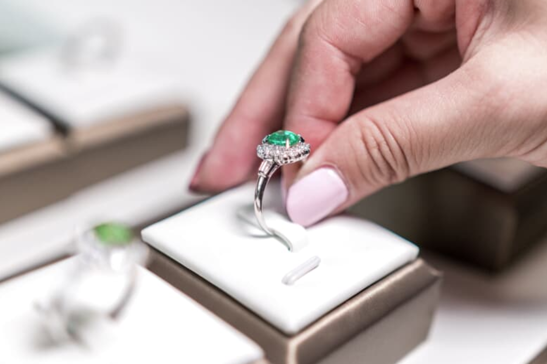 A woman inserts an emerald ring to a ring box