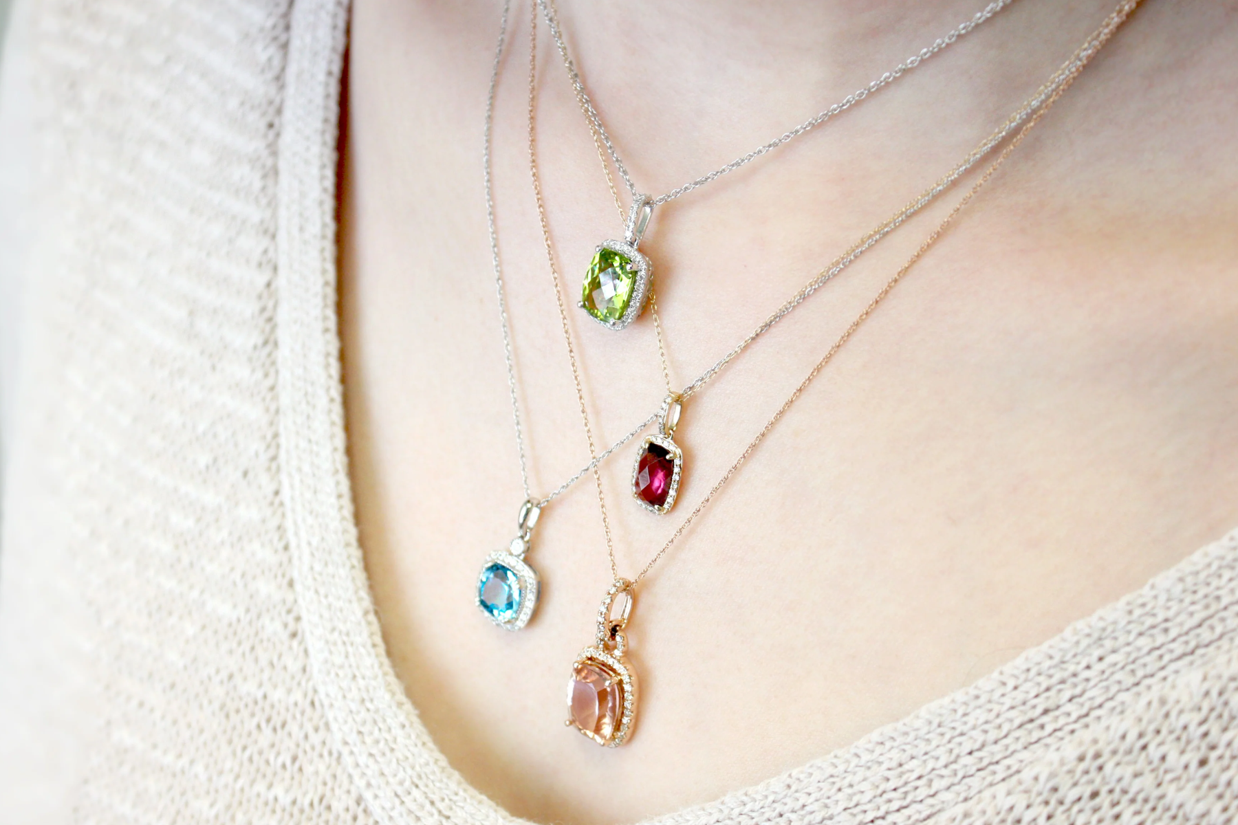 A woman's neck is adorned with four birthstone necklaces