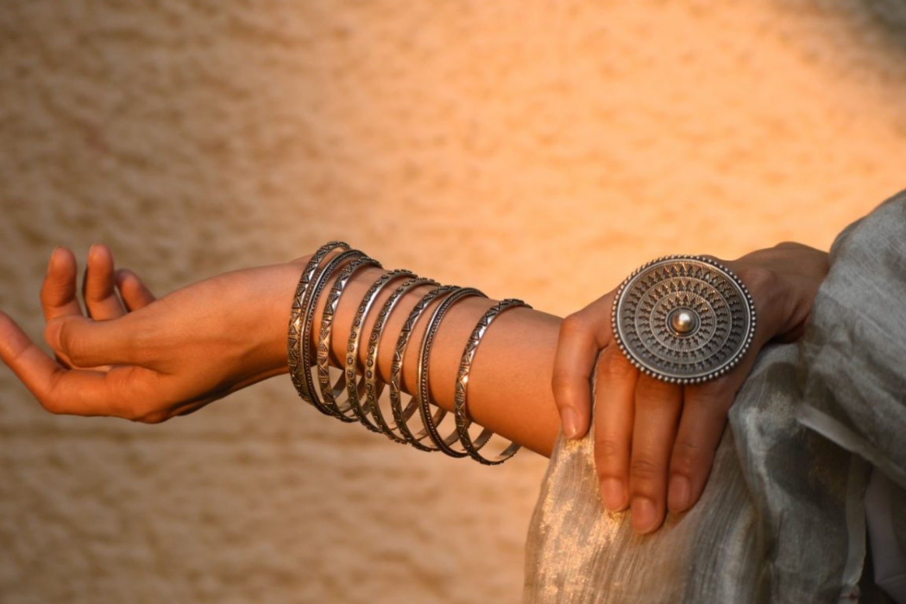 A woman wearing a spiral handcrafted silver bracelet and a ring in front of the sunrise