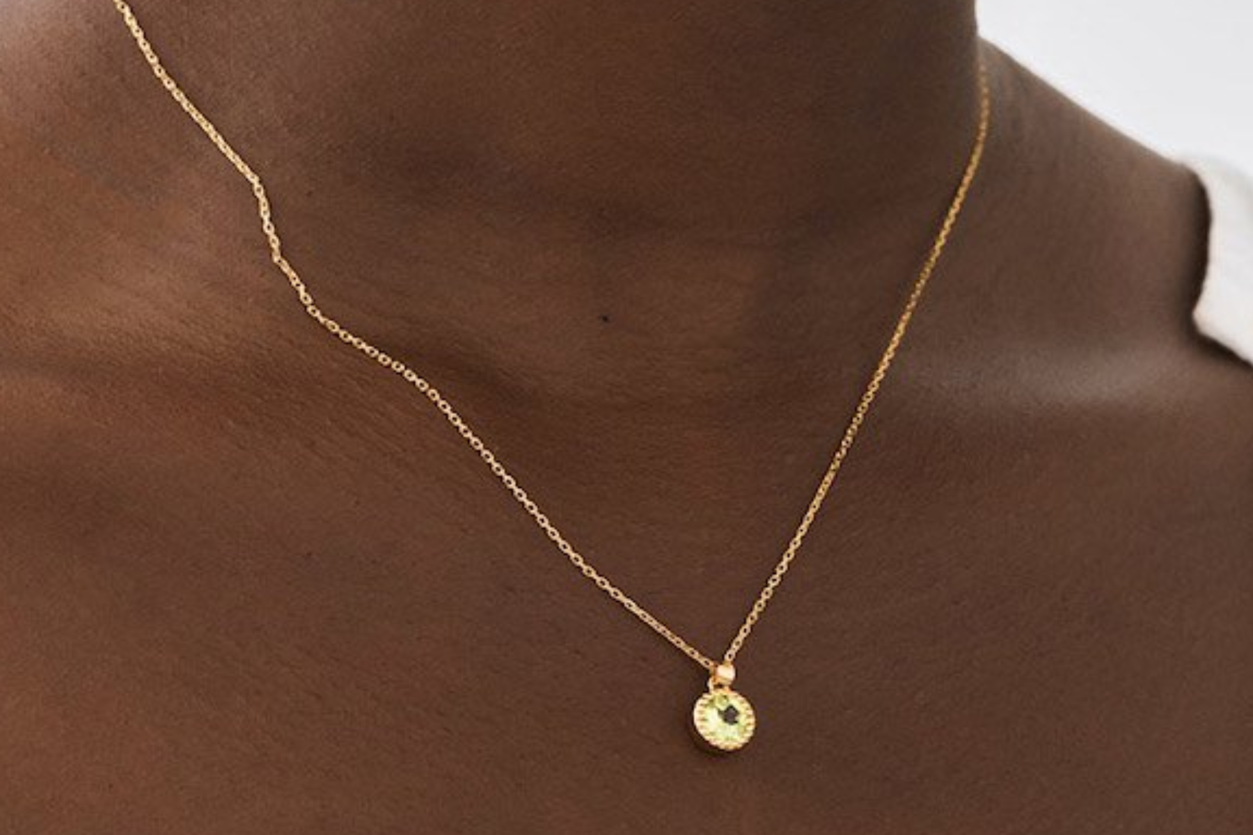 A black woman wearing a necklace with a gold pendant