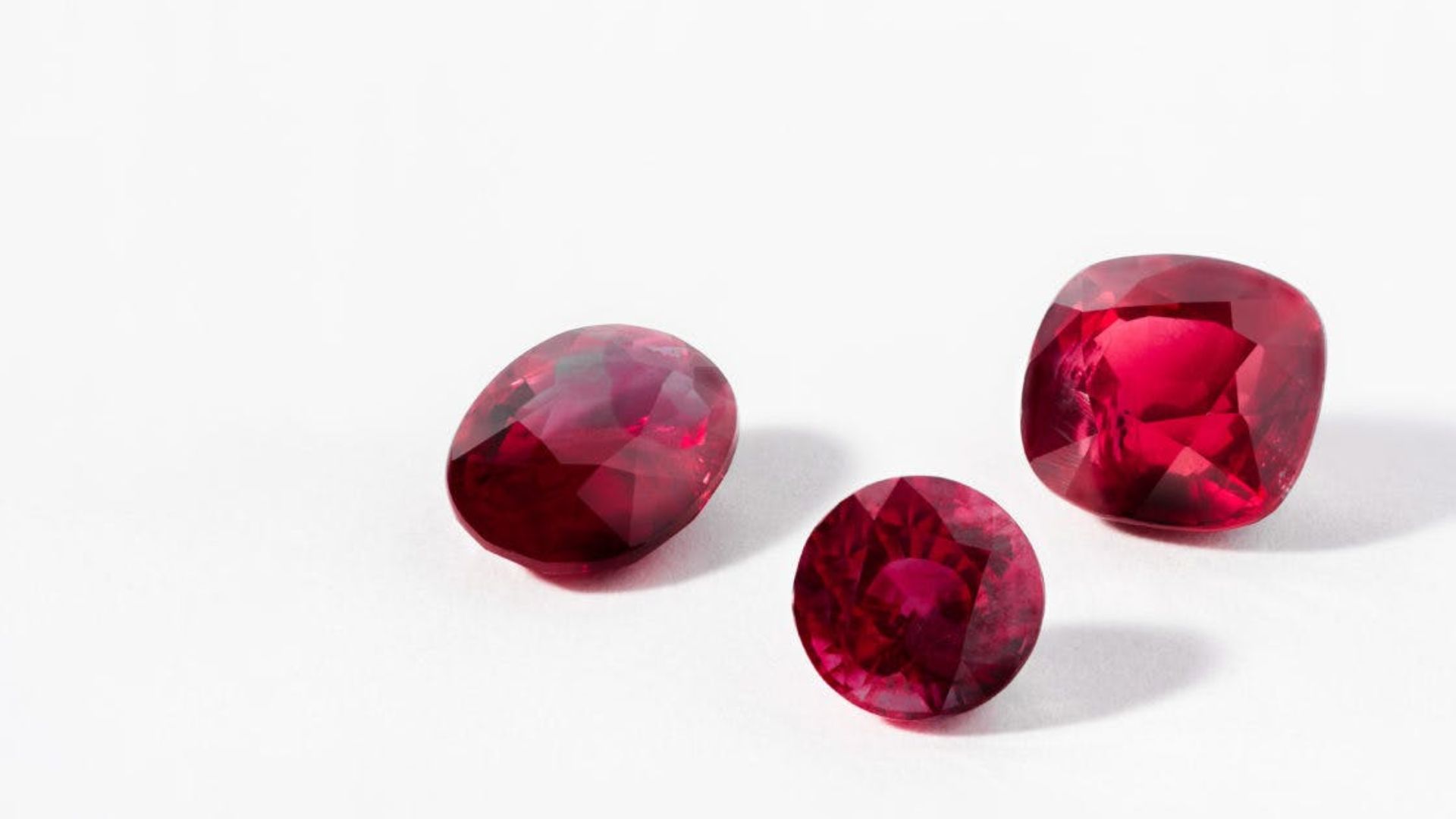 3 Red Colored Gemstones On White Surface