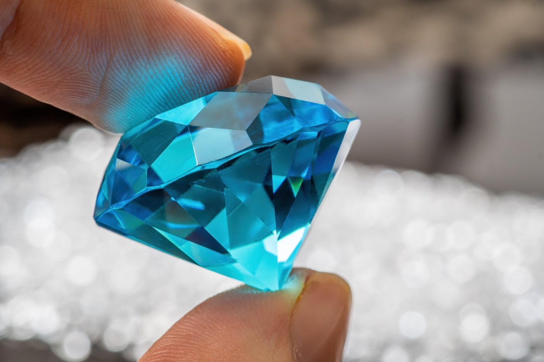 A hand inspecting a blue gem