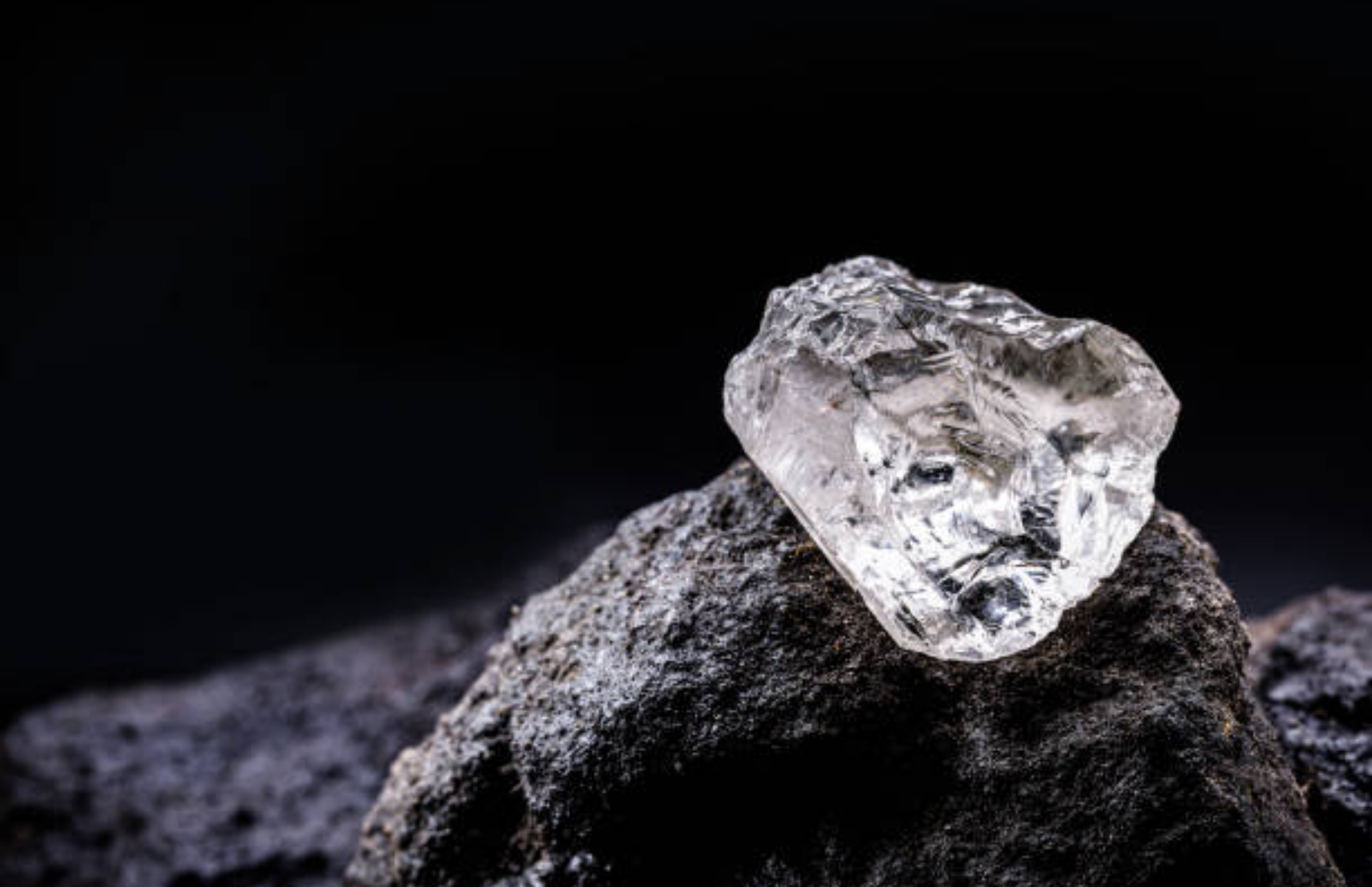 A clear diamond stone rests on a rock