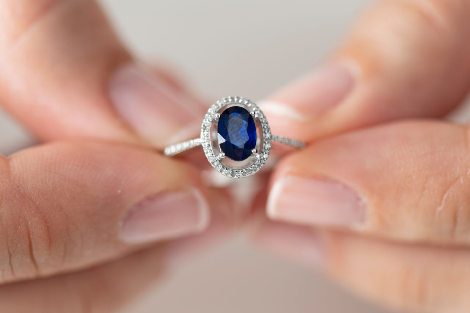A woman's hand holding a blue sapphire stone ring