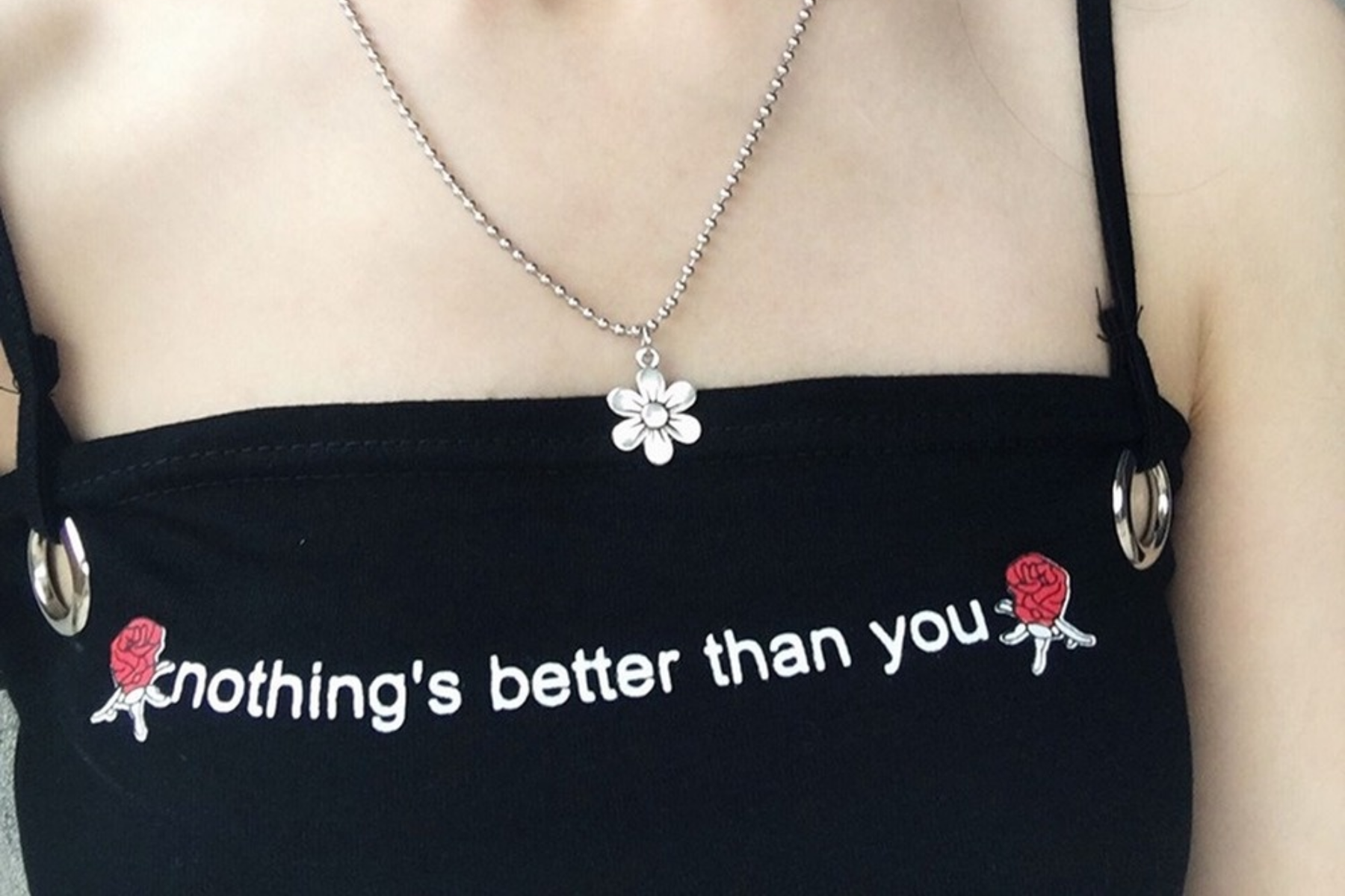 A woman wearing a simple black sleeveless shirt with the phrase "nothing's better than you" and a flower pendant