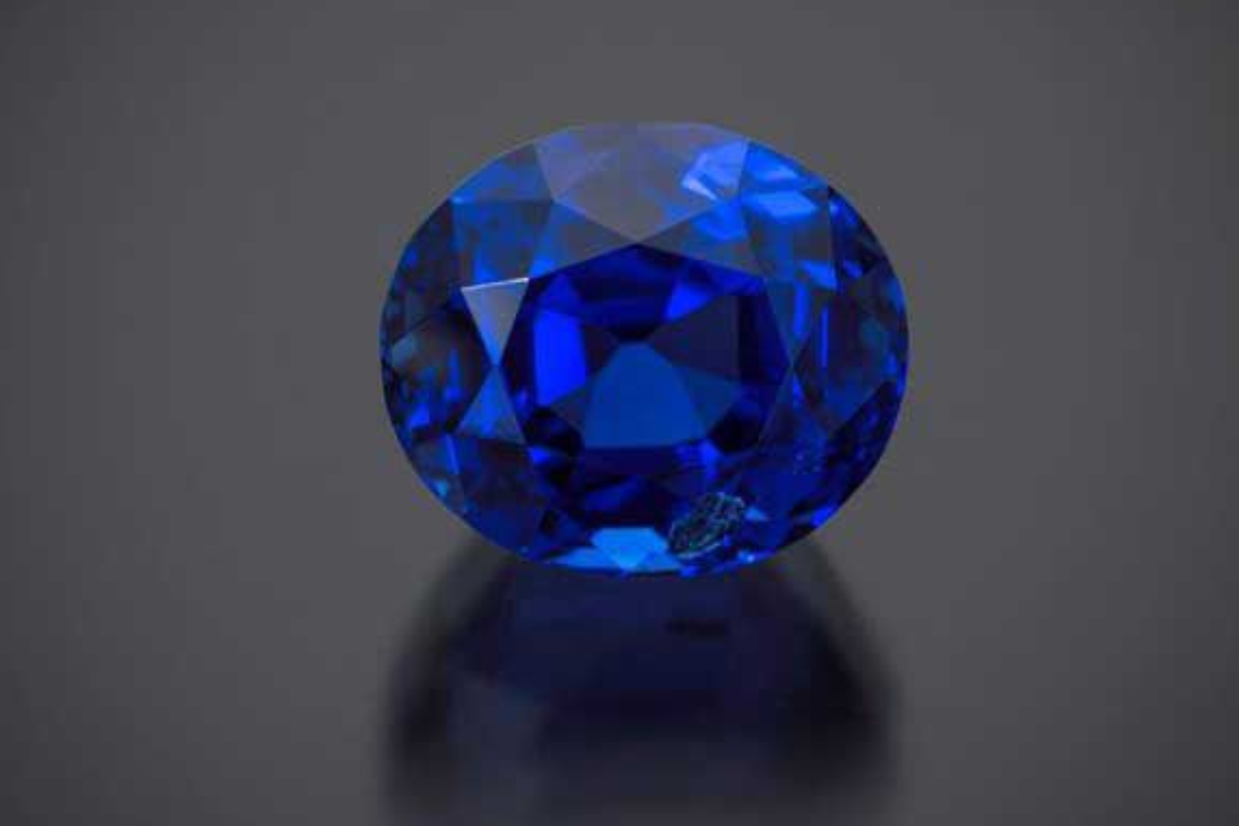 A small piece of Blue Sapphire stone on a dark gray setting