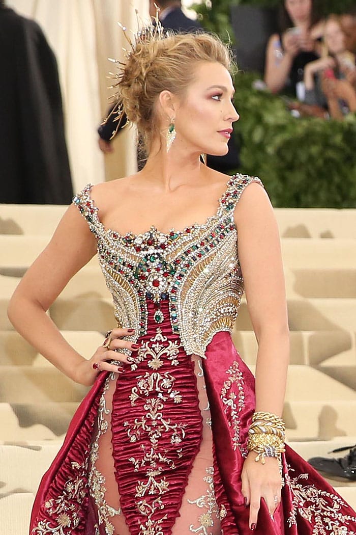 Blake Lively wearing a red and golden dress with a star ruby ring