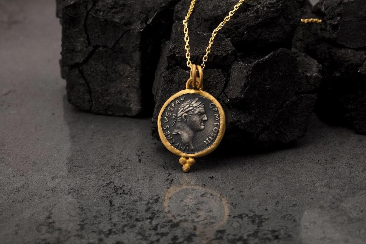 A necklace of gold coins resting on a dark rock
