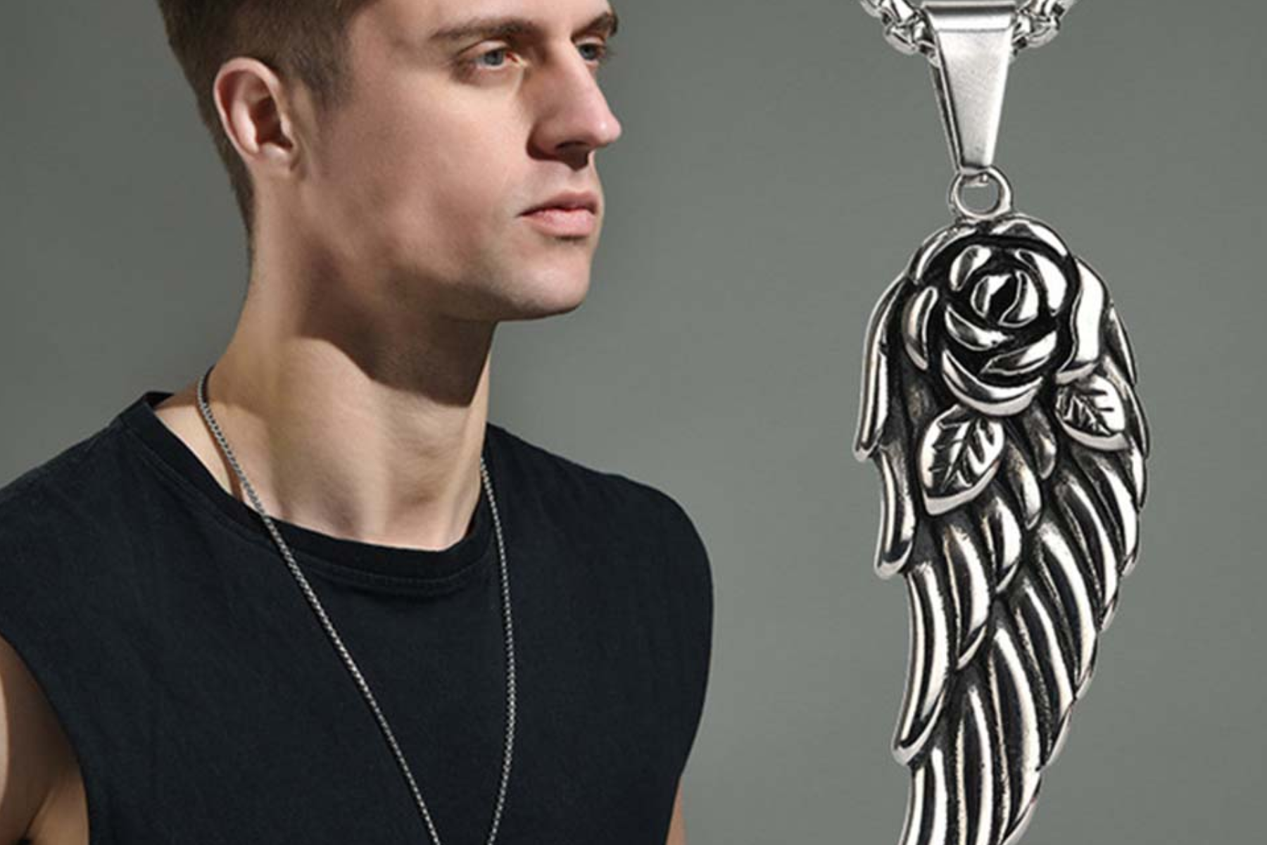 A man stands in front of a necklace with an angel wing pendant