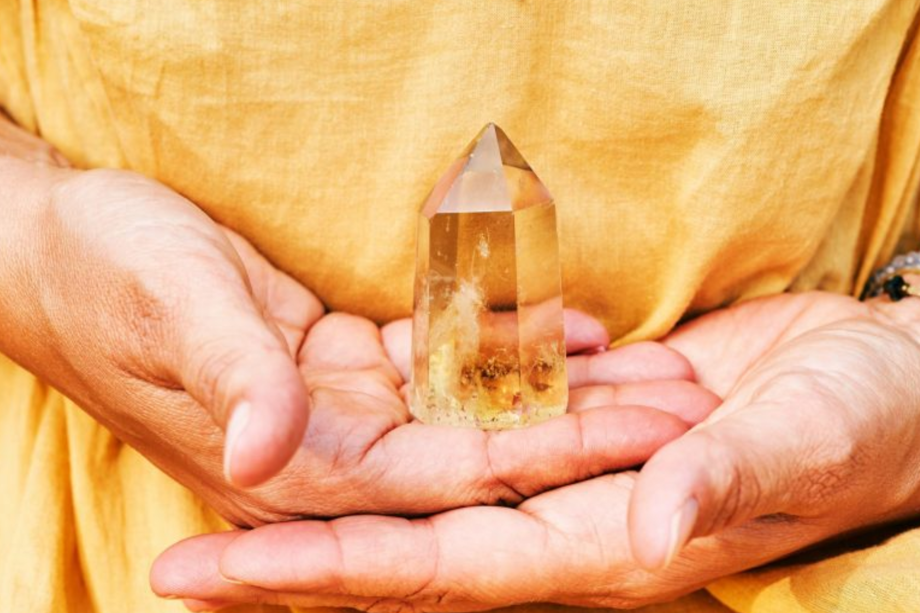 A woman dressed in yellow holds citrine in both hands
