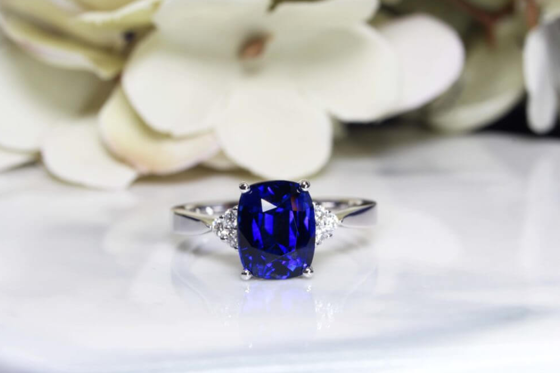 Sapphire stone ring with white flowers behind