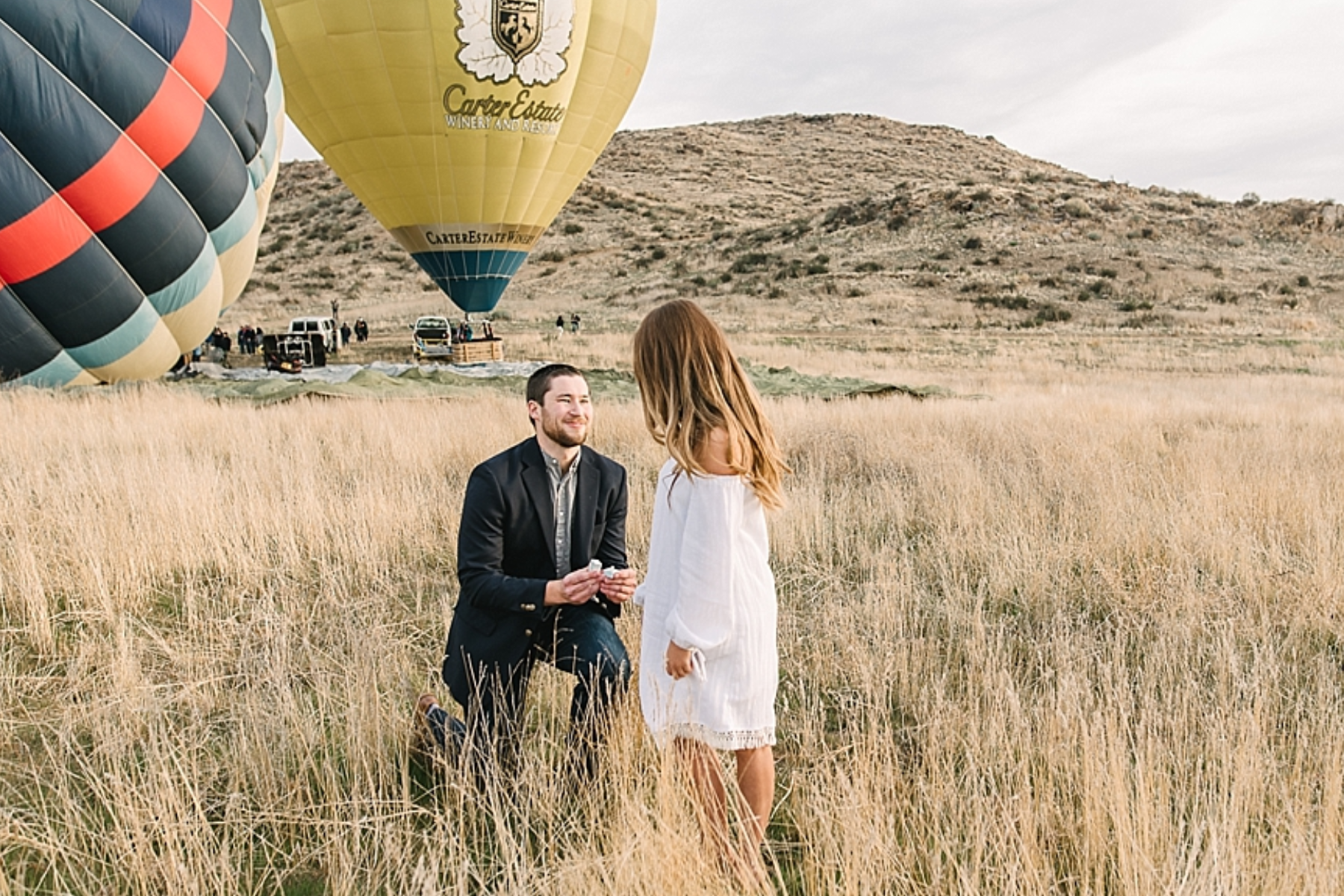 A man proposes to his partner in front of a massive hot air balloon