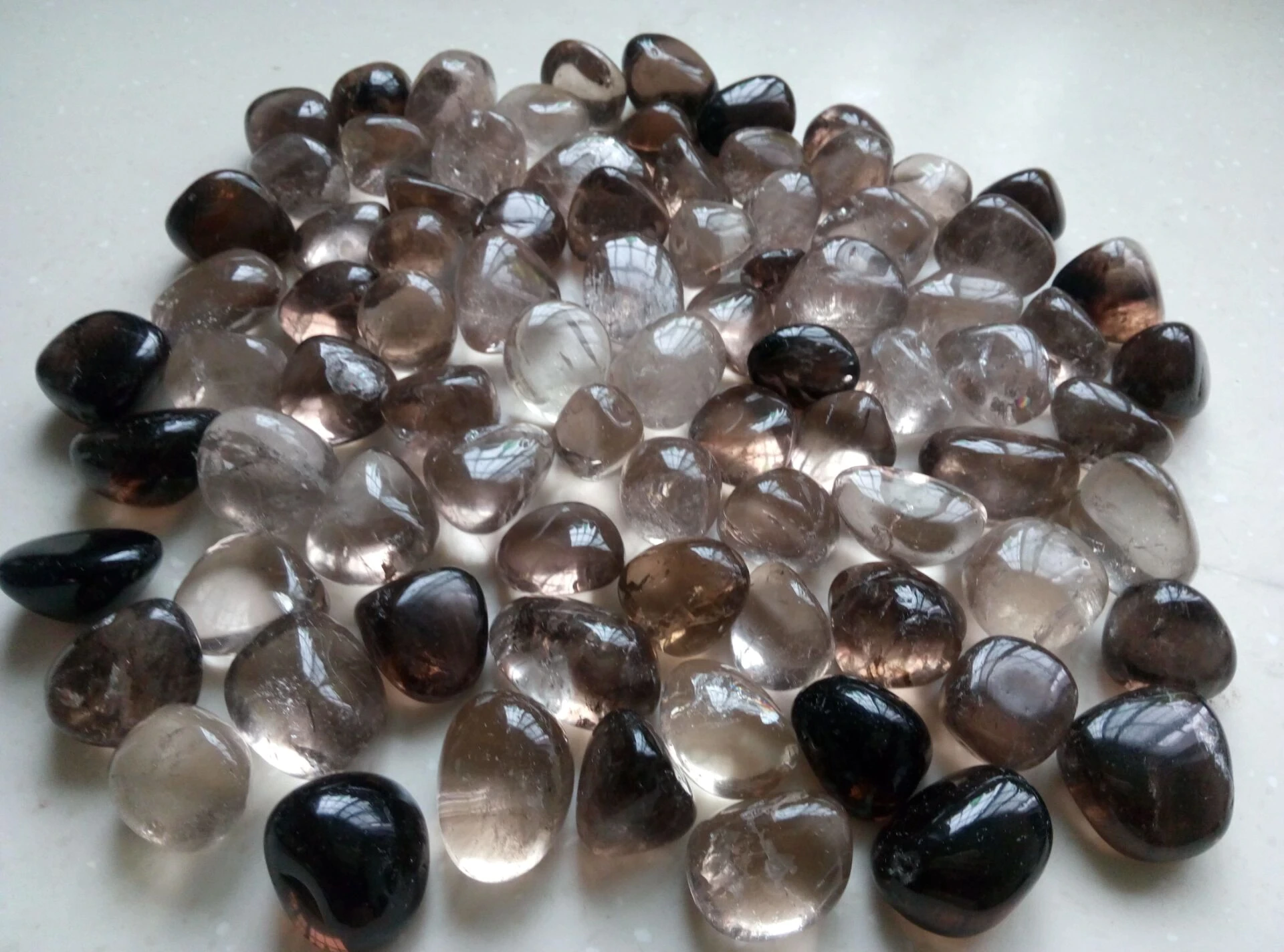 A Number Of Polished Smoky Quartz Crystals On White-Colored surface