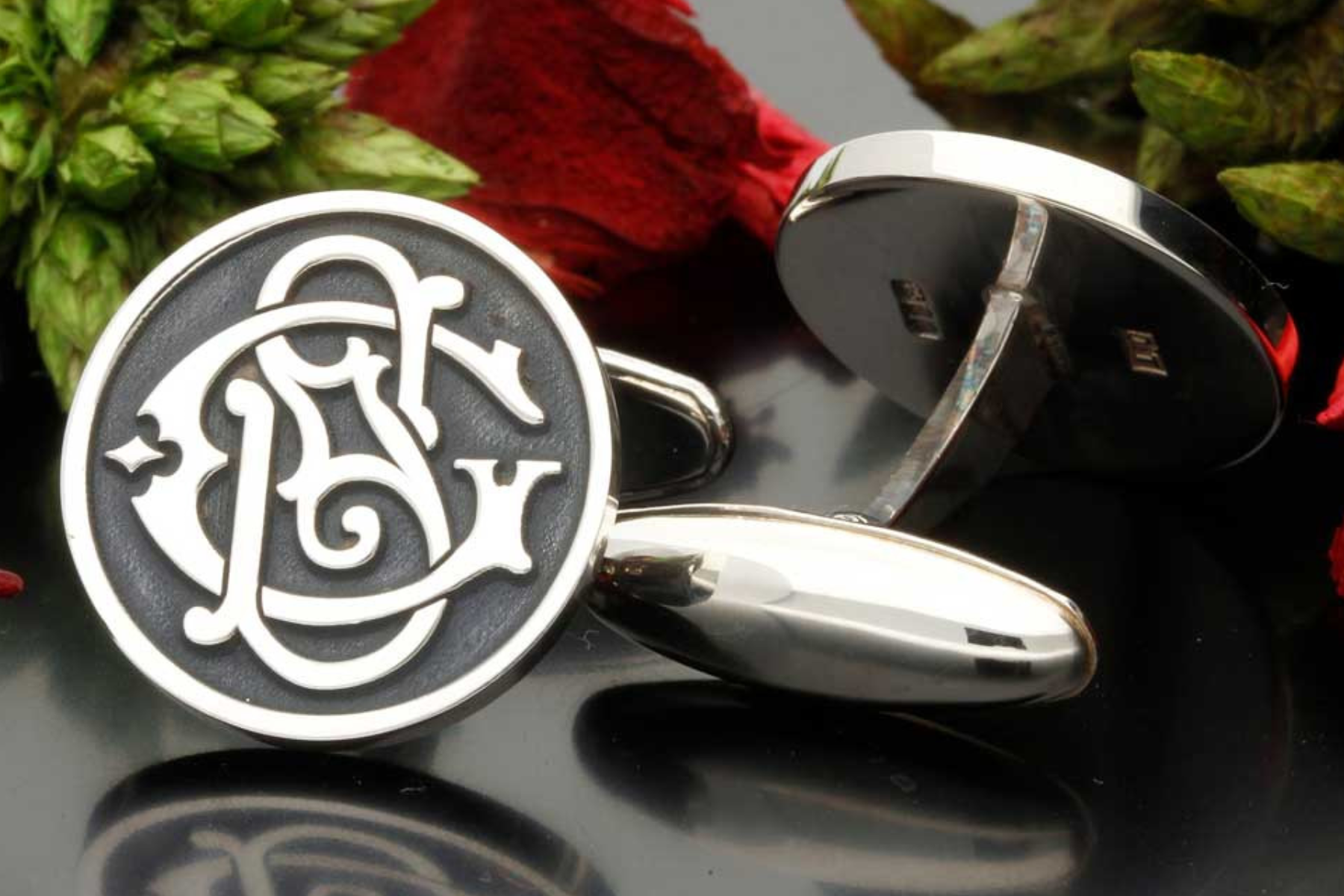 A pair of monogrammed cufflinks displayed on a glass table